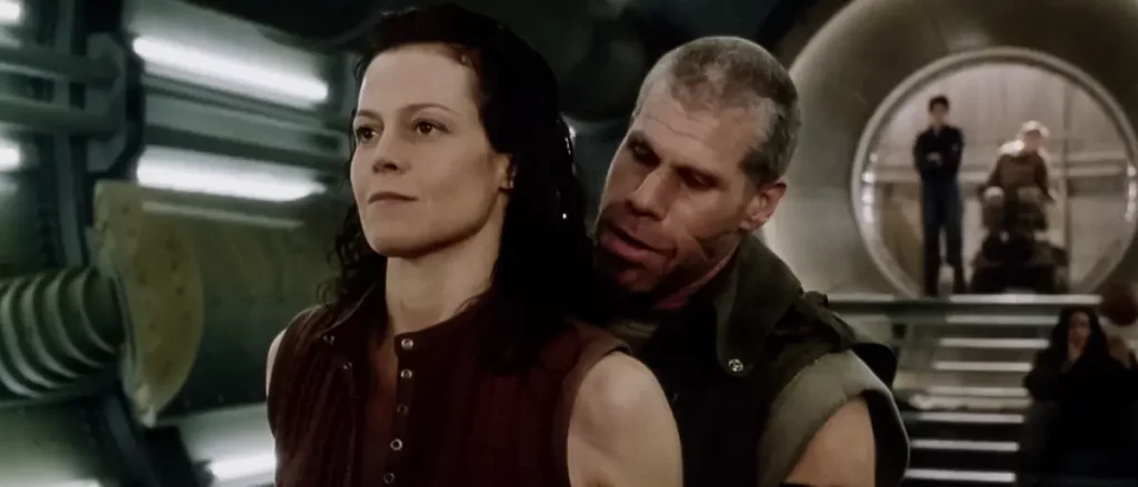 Ellen Ripley steht in der Basketballhalle in Alien: Resurrection, während Johner dicht hinter ihr positioniert ist, um an den Ball zu gelangen. Beide Charaktere sind von Brusthöhe bis Kopf zu sehen, mit angespannter Atmosphäre.